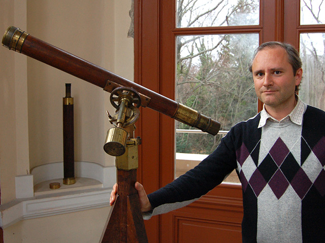 Der Astronom Thomas Posch hält ein älteres Fernrohr an der Universitätssternwarte in Wien