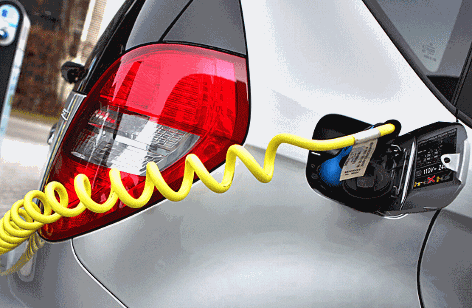 Ein Elektroauto wird mit einem Stromkabel an einer Ladesäule mit Ökostrom geladen.