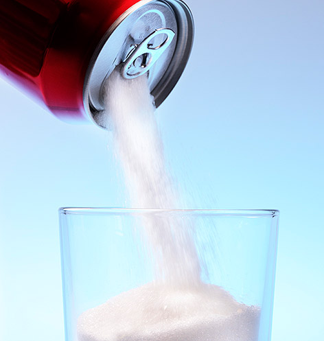 Zucker wird aus einer Dose in ein Glas geleert.