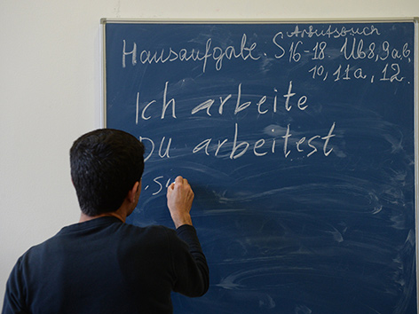 Ein Asylwerber schreibt auf eine Tafel