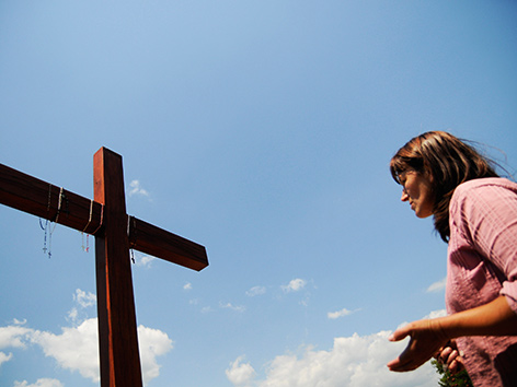 Eine Frau betet vor einem Holzkreuz in Medjugorje