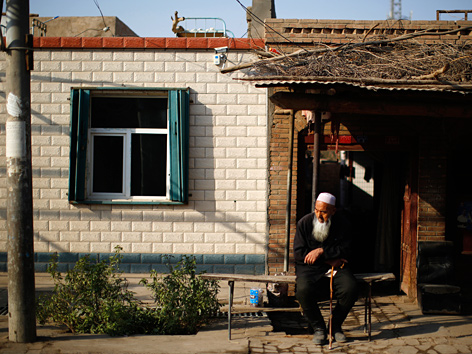 Ein uigurischer alter Mann sitzt vor seinem Haus in der chinesischen Provinz Xinjiang