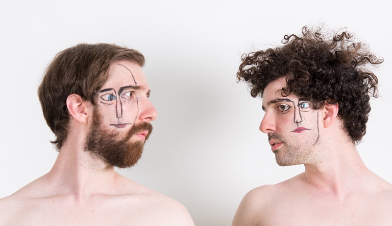 Zwei nackte Männer mit aufgemalten Gesichtern