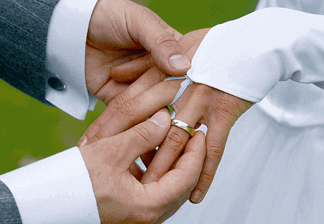 Ein Bräutigam streift bei der Trauung seiner Braut den Ehering über den Finger