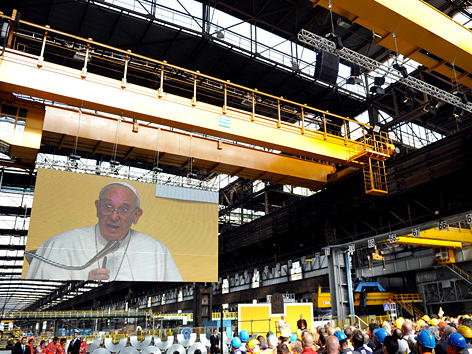 Papst Franziskus auf einem Bildschirm, Rede vor Arbeitern eines Stahlwerks in Genua, Italien