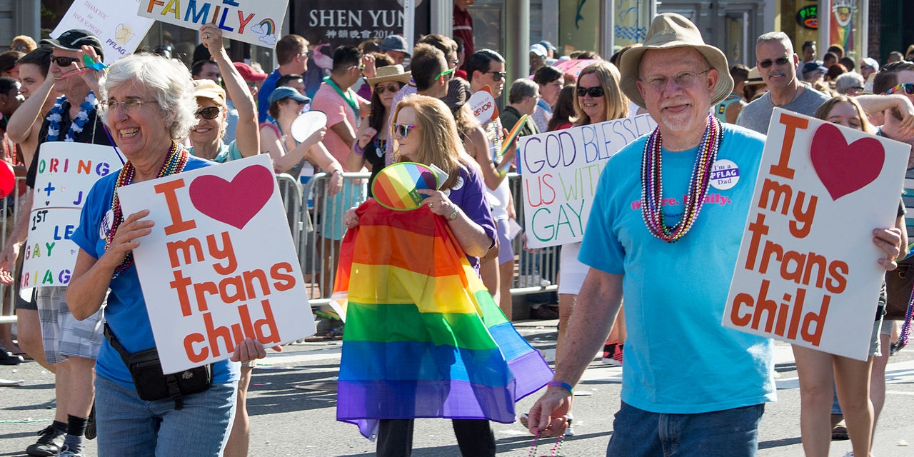 Eltern mit Schildern bei einer Pride Veranstaltung