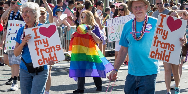 Eltern mit Schildern bei einer Pride Veranstaltung