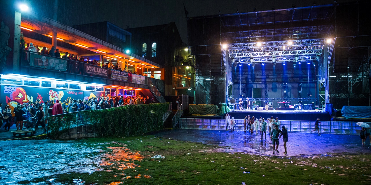 Menschen im Regen vor einer leeren Bühne