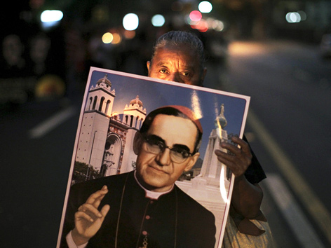 Eine Frau hält ein Plakat mit einem Foto von Oscar Romero hoch