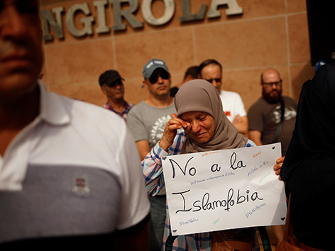 Eine muslimische Frau weint und hält ein Schild mit der Aufschrift "Nein zu Islamophobie"