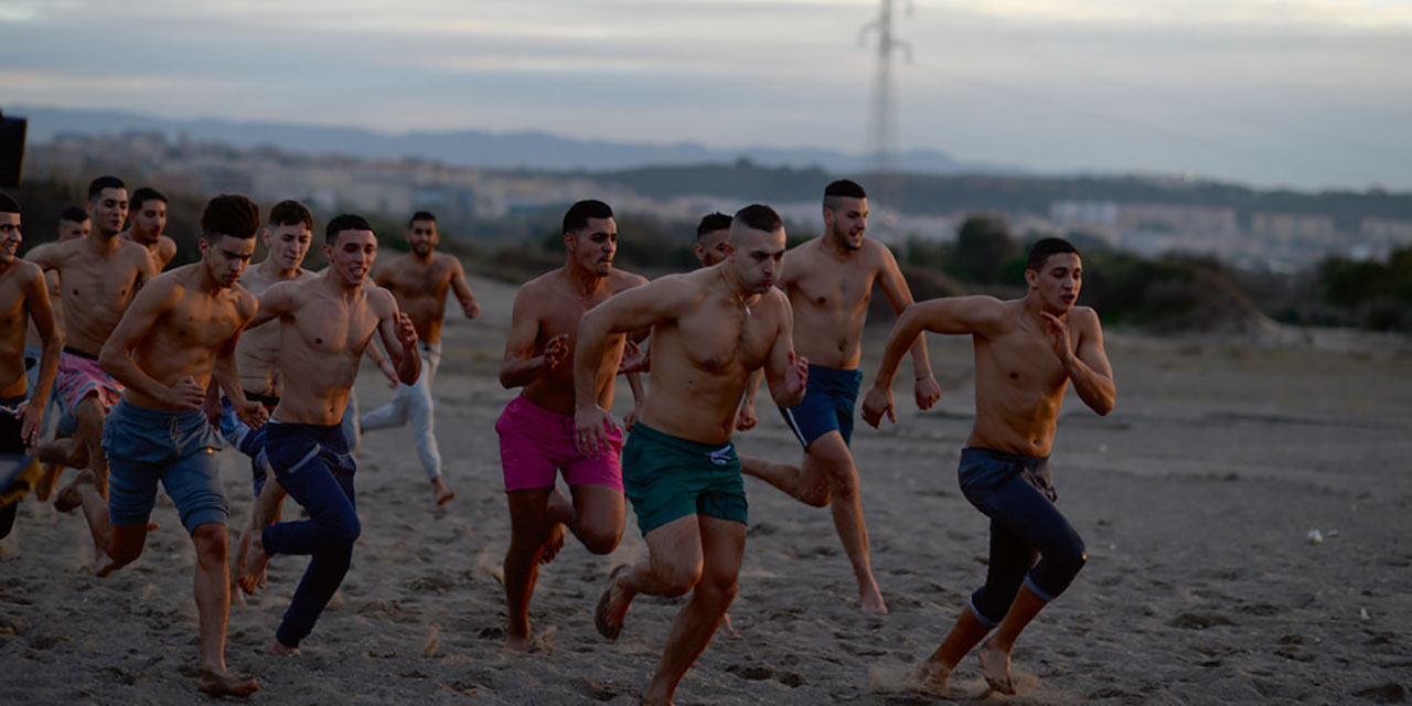 Viele junge Männer laufen über einen Sandstrand