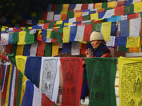 Eine Tibeterin beim Beten inmitten von Gebetsfahnen