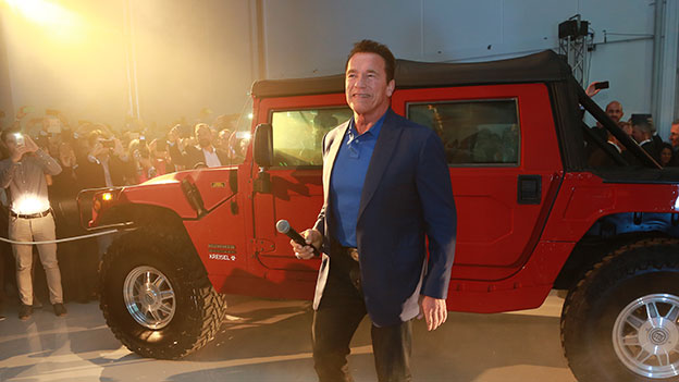 Arnold Schwarzenegger vor einem roten Elektro-Hummer