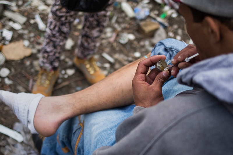 A man loads a syringe near a heroin encampmentin the Kensington neighborhood of Philadelphia