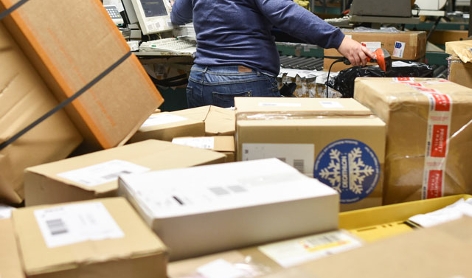 Mitarbeierin in einem Paketzentrum scannt Pakete