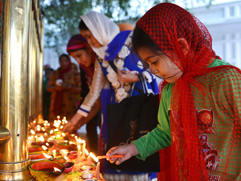 Ein Sikh-Mädchen entzündet Kerzen zu Diwali am Goldenen Tempel in Amritsar, Indien