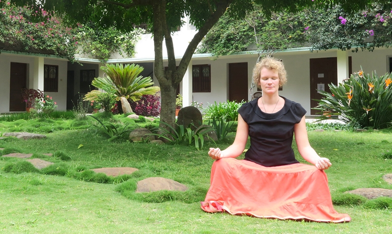 Meditierende junge Frau in einem Garten
