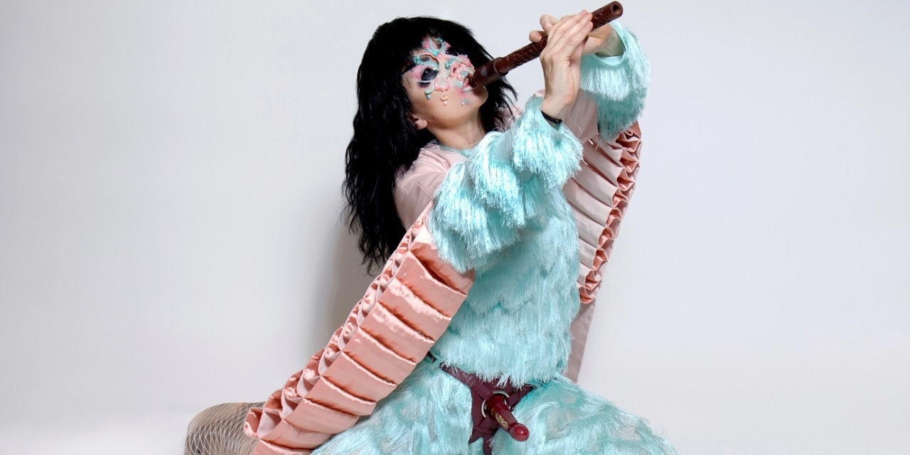 Björk mit türkisem Pelz und Strap On