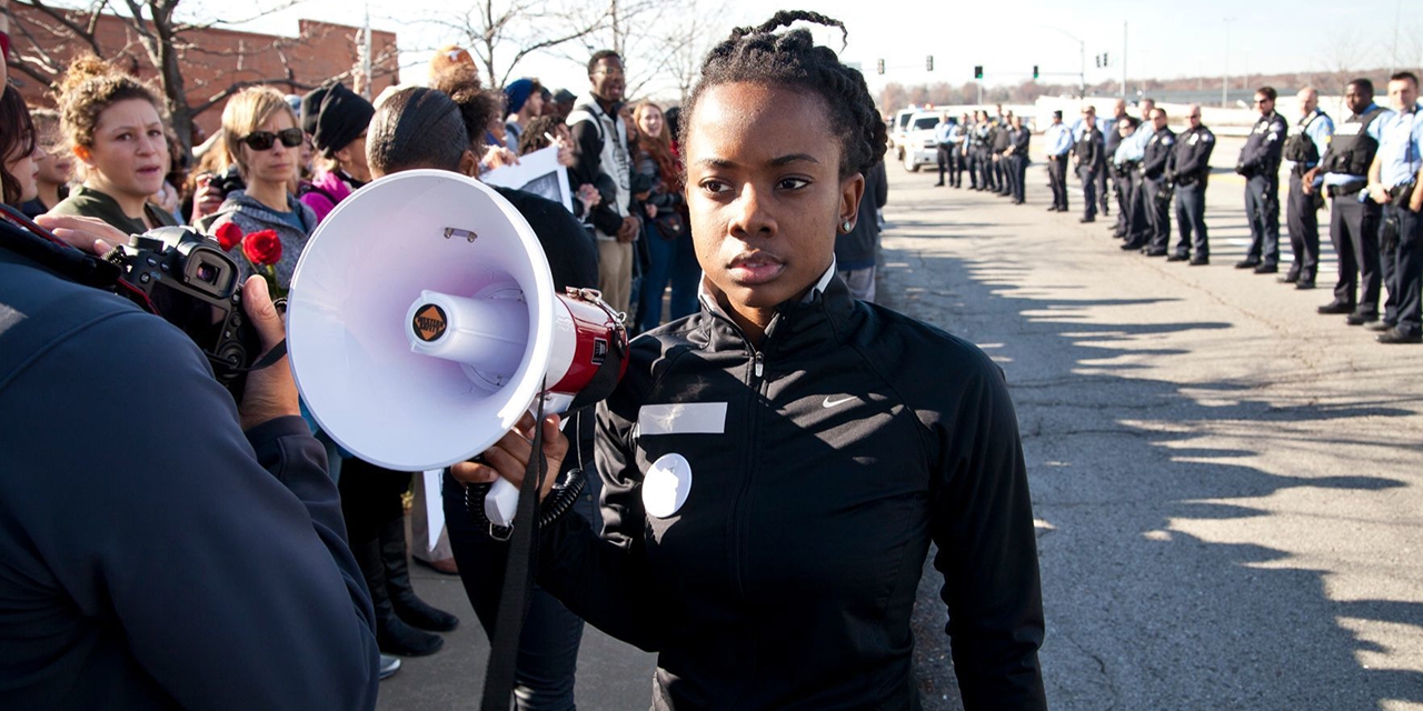 Eine schwarze Frau protestierend mit Megaphon, Filmstill aus "Whose Streets"