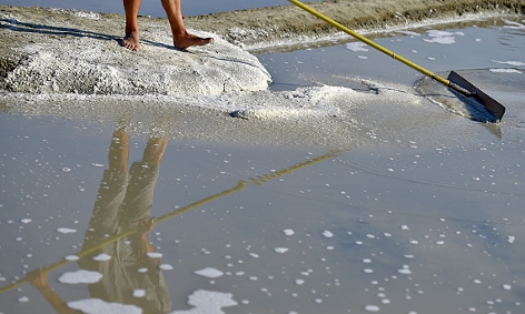 Ein Salzarbeiter erntet das Salz von der Wasseroberfläche