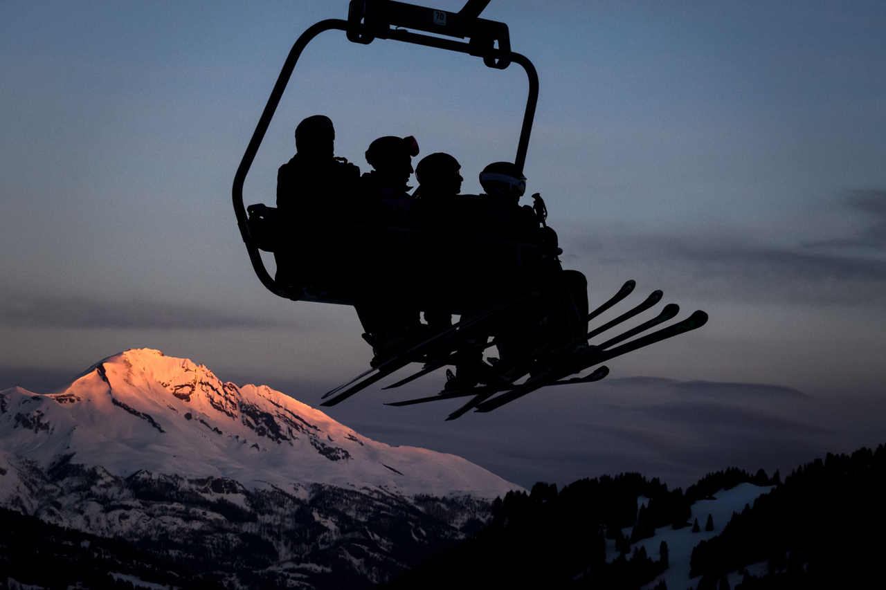 Skiers are seen in silhouette on a ski lift as the sun rises next the resort of Lenzerheide, eastern Switzerland