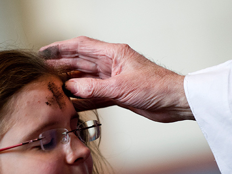 Ein Mädchen bekommt ein Aschekreuz auf die Stirn