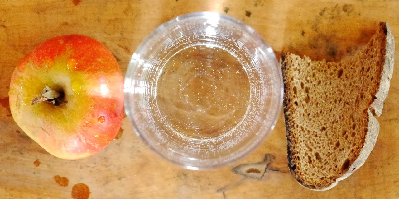 Apfel, leere Schale und ein Stück Brot
