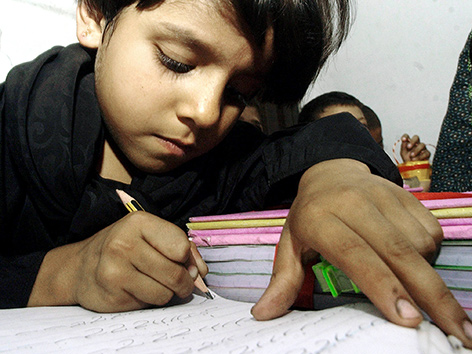 Ein Schulkind schreibt an einem Tisch sitzend