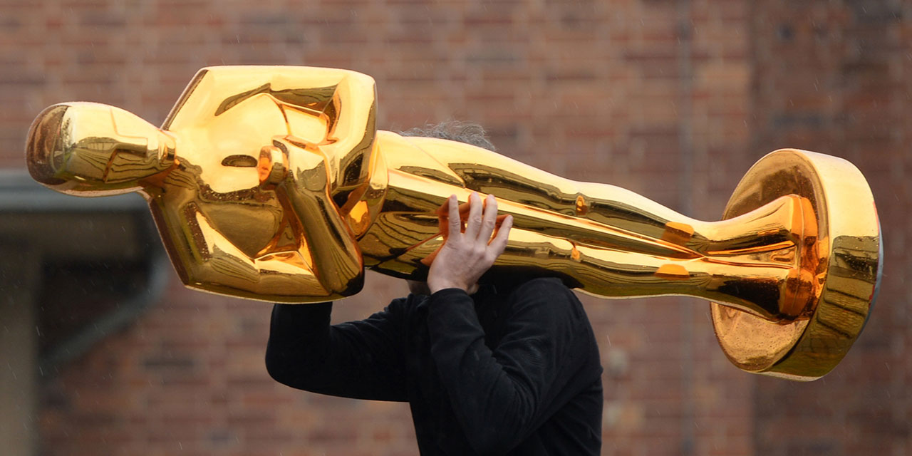 Mann trägt große Oscar-Statue auf der Schulter