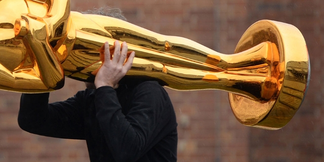 Mann trägt große Oscar-Statue auf der Schulter