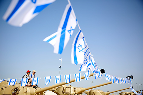 Kinder sitzen am israelischen Memorial day auf einem Panzer
