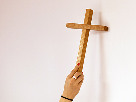 Eine Frau hängt ein Kreuz an eine Wand