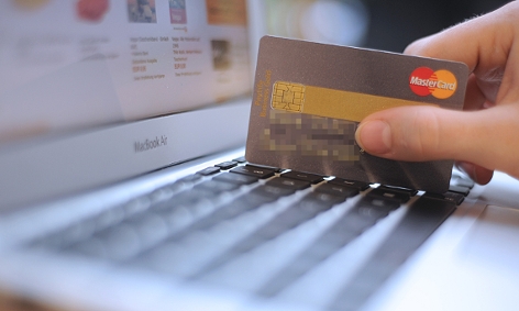 Ein Mann zückt seine Kreditkarte zum Einkaufen im Internet
