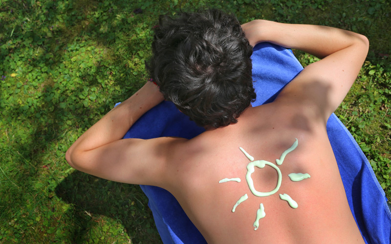 Sonne aus Sonnencreme auf Rücken gezeichnet