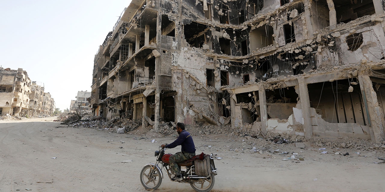 Zerschossene Häuserfront in Damaskus, davor ein Mann auf dem Fahrrad