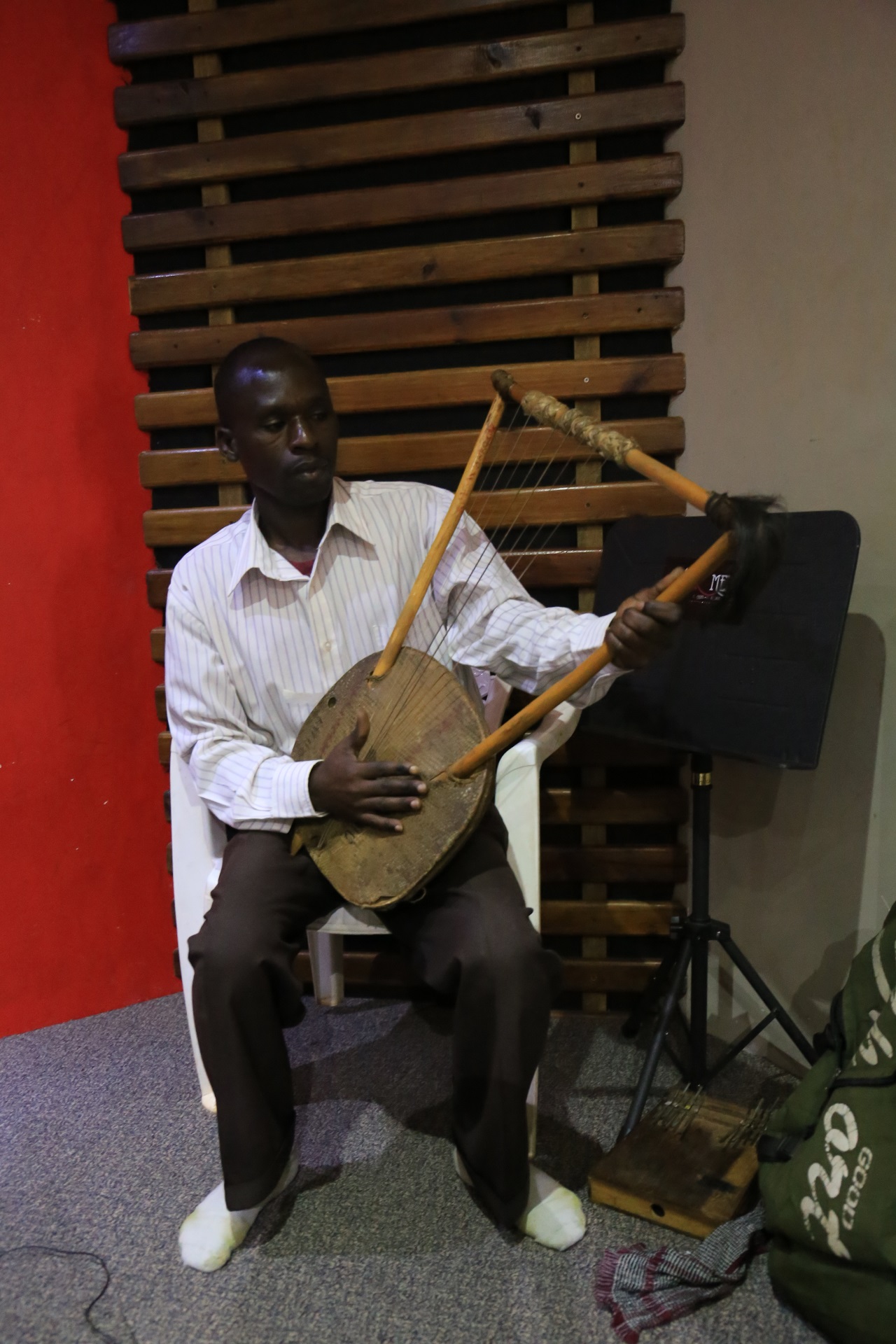 Ugandischer Musiker mit einer Adungu (Harfenähnliches Instrument) im Studio