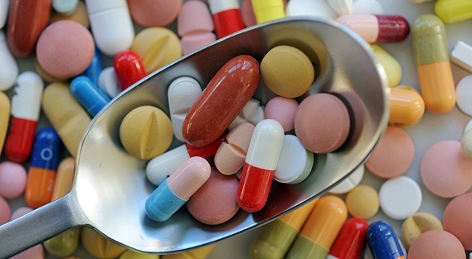 Verschiedene Pillen und Tabletten liegen auf einem Löffel