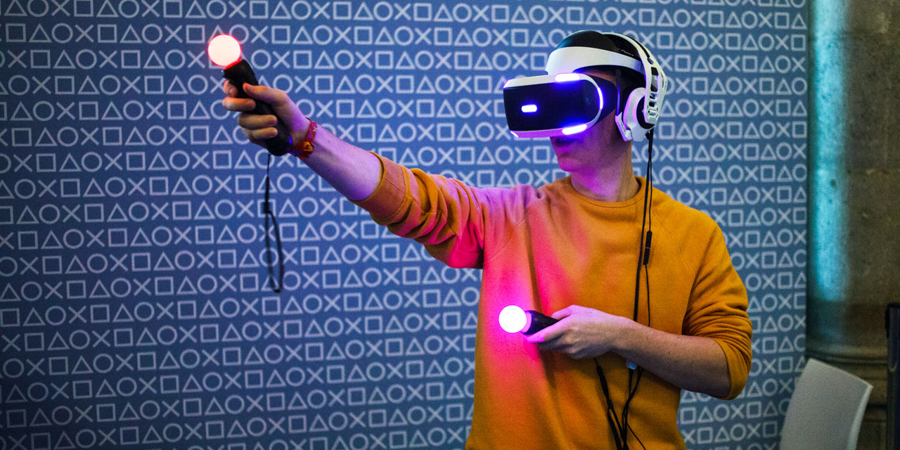Person mit VR-Brille und leuchtenden Game-Controllern