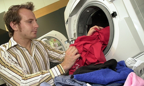 Mann füllt Wäsche in eine Waschmaschine