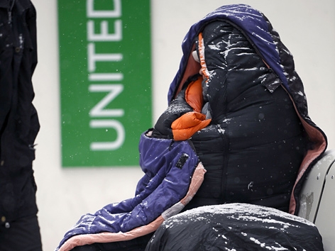 Obdachloser im Winter. Sitzt in der Kälte auf einer Bank