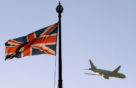 Ein Flugzeug fliegt an einer britischen Flagge am Victoria Tower des Palace of Westminster vorbei