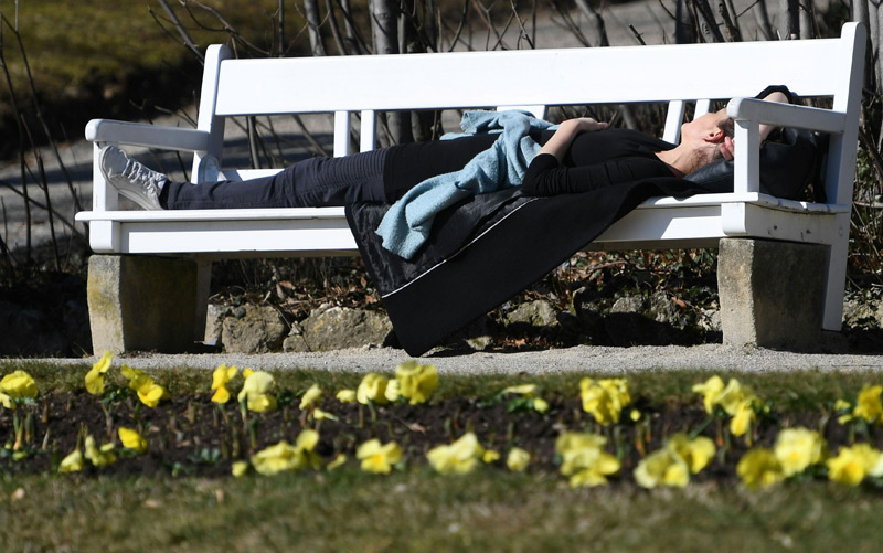 Frau liegt auf einer Parkbank im Frühling