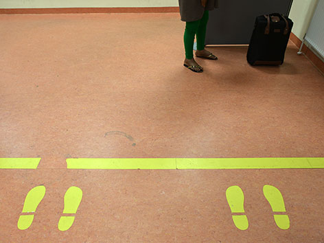 Gelbe Schuhabdrücke vor einer gelben Linie in einem Asylberatungszentrum