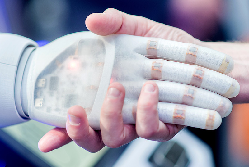 Ein Mann hält die Hand eines bionischen Roboters