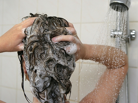 Eine Frau unter der Dusche wäscht sich ihre Haare