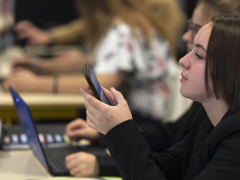 Eine Schülerin in der Klasse mit Smartphone