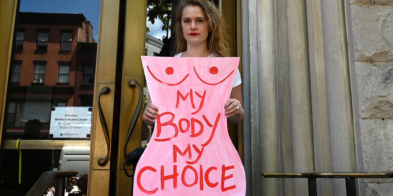 Eine Frau mit einem Pappschild und der Aufschrift: Mein Körper, meine Entscheidung
