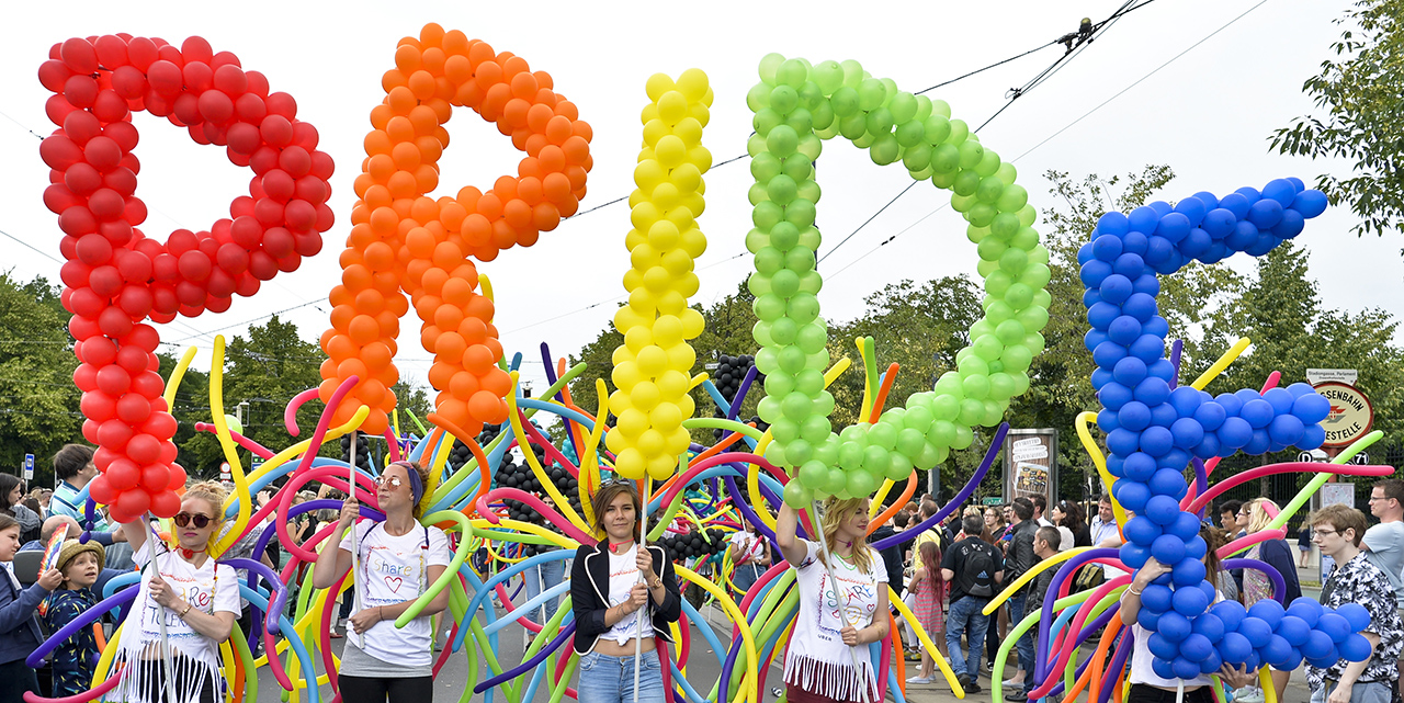 Menschen auf der Regenbogenparade mit PRIDE-Schrift