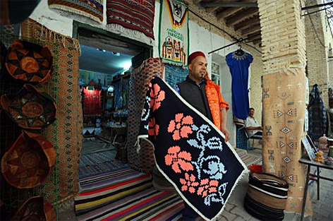 Ein Teppichhändler zeigt seine Waren am Markt in Tozeur im Süden von Tunesien