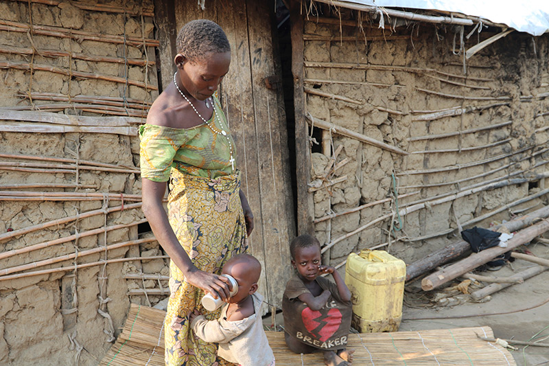 Frau in Burundi gibt ihrem Kind Wasser zu trinken